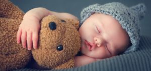 a baby sleeping while cuddling a teddy bear