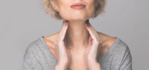 woman feeling her thyroid glands in her neck