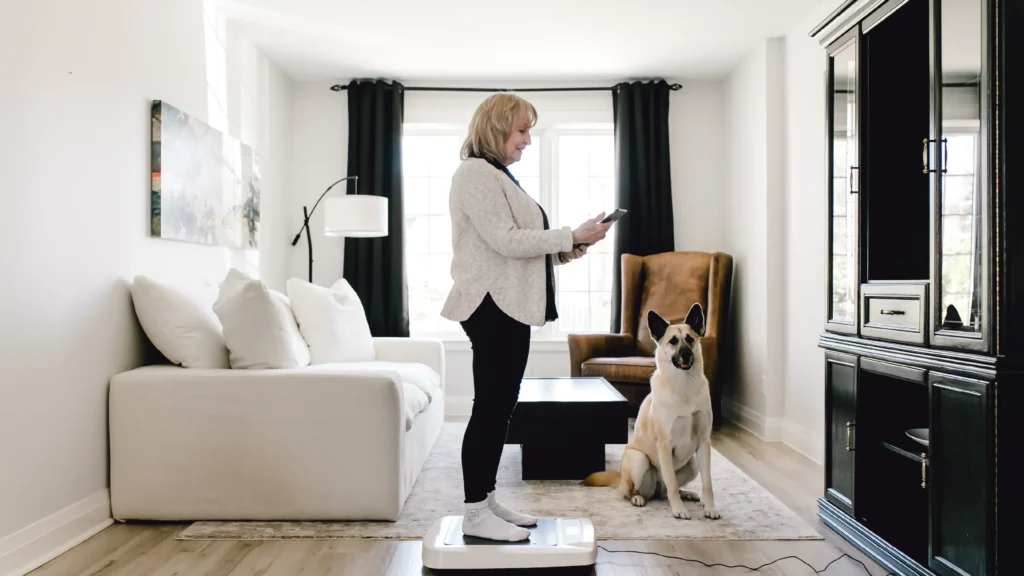 Woman using a digital health monitoring device at home with her dog nearby